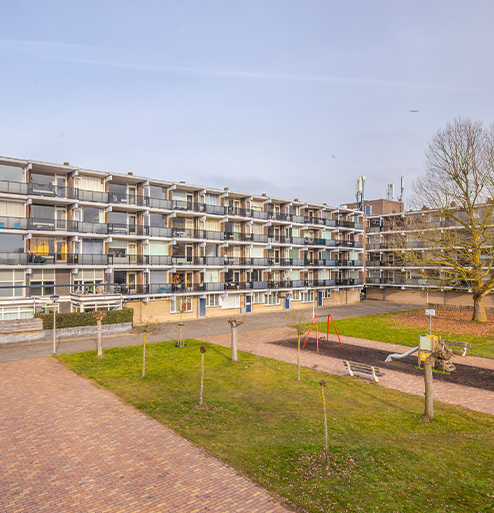 Appartementencomplex met balkons rondom een groene binnentuin met speeltoestellen