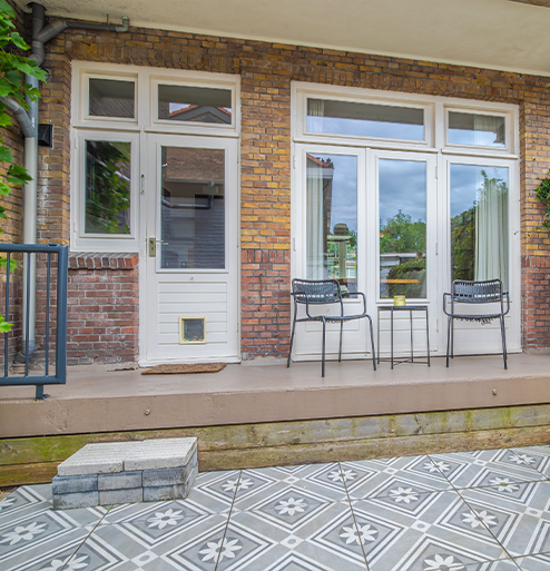 Beschutte stadstuin met betegeld terras, openslaande deuren en zitgedeelte