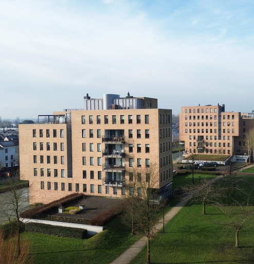 Luchtfoto van moderne bakstenen appartementencomplexen met park en waterpartij