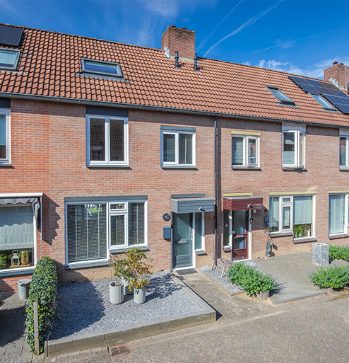 Bakstenen rijwoningen met zonnepanelen op het dak en verzorgde voortuinen
